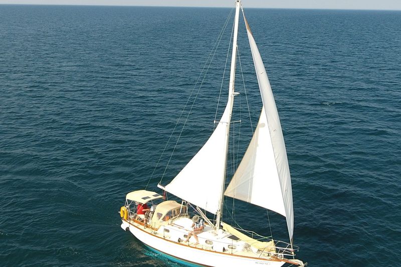 1984 Cape Dory 30 sailboat cruising on open sea under clear skies.