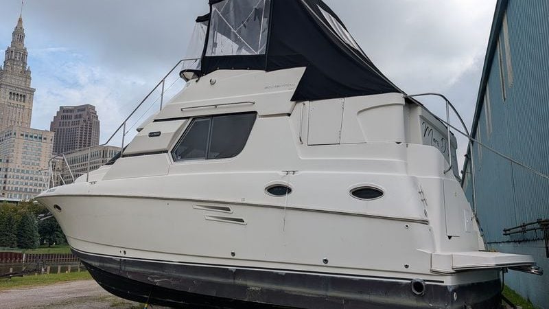 1990 Silverton 322 Motor Yacht docked near urban buildings, featuring sleek white design.