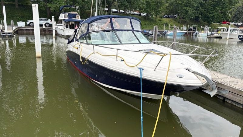 2005 Sea Ray 290 Sun Sport docked at a marina, surrounded by lush greenery.